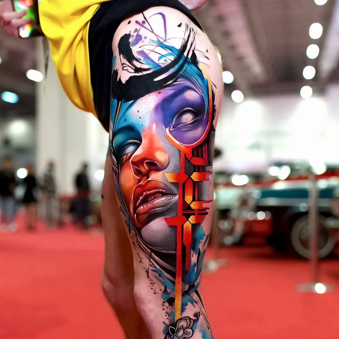 Colour realism tattoo by Starletink: face with brush strokes and red geometric shapes, leg piece